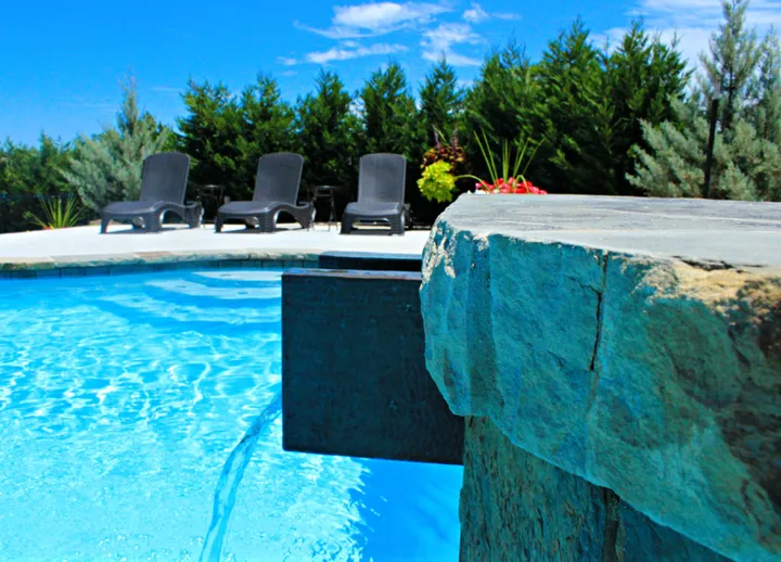 Pool with artistic stone water feature and spa with vegetation